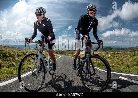 Radfahren Paar klettern Große Dun fiel in den Pennines, Cumbria, Großbritannien Stockfoto