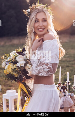 Bezaubernde Braut mit Tiara auf Natur Hintergrund. Moderne Braut Stil. Boho Fashion Hochzeit. Gefilterte Kreuz verarbeitet Foto mit Bokeh und Kopieren. Stockfoto