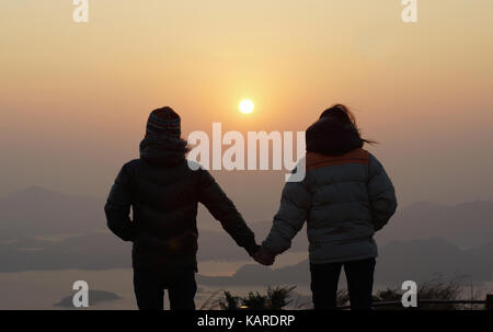 Glückliches Paar gefunden, Szenen mit Hintergrundbeleuchtung, erster Tag Hand in Hand sunrise ein neues Jahr Flitterwochen, Wandern auf den Gipfel, seaview Landschaft mit beaut Stockfoto