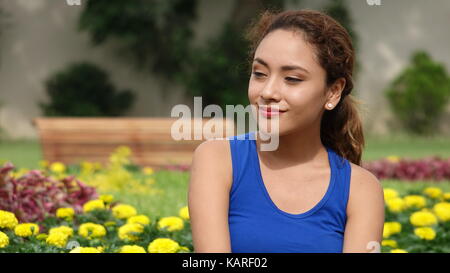 Junge Frau sitzt im Blumengarten Stockfoto