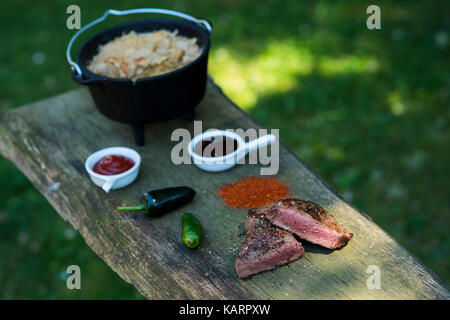 Fleisch und holländischen Ofen auf einem Garten Grill Stockfoto