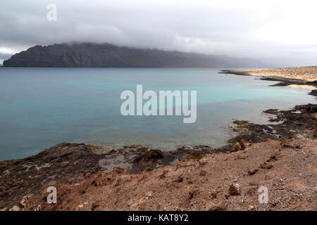 Blick auf ruhigen Meer, Wolken Risco de Famara Klippen, die Insel La Graciosa, Lanzarote, Kanarische Inseln, Spanien Stockfoto