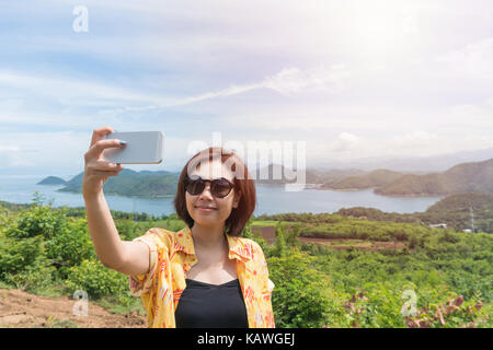 Weibliche Reisende selfie mit Ihrem Smart Phone und schöne Landschaft bei kanchanaburi Thailand Stockfoto