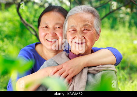 Foto von einem ausgereiften chinesische Frau mit ihrem älteren Mutter draußen im Hof Stockfoto