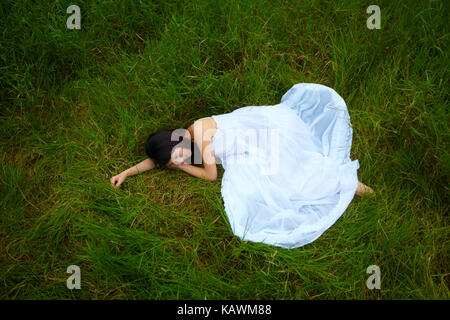 Attraktive junge asiatische Frau mit weißem Kleid an der frischen outdoor Wiese Stockfoto