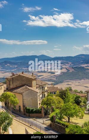 Vertikale Foto mit alten rustikalen Haus, das an der Seite der historischen Stadt in der Toskana Italien gebaut wird. Die Landschaft mit Hügeln, Felsen, Olivenbäumen und Wald Stockfoto