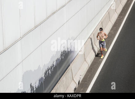 Hohe Sicht auf den Mann, der auf der Straße joggt. Stockfoto