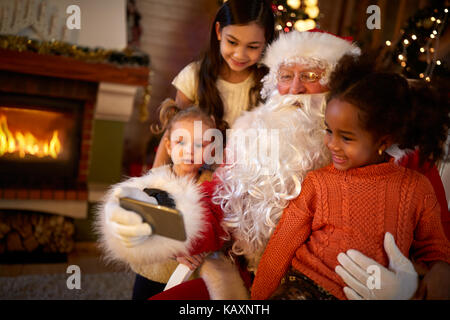 Santa claus Macht selfie mit drei netten Mädchen Stockfoto