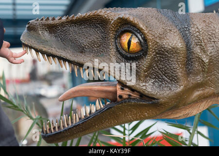 Den Finger des kleinen Kind fühlt sich ein vorderer Zahn eines Fiberglas Werbung außerhalb der Dinosaurier Dinosaur World, Torquay, Devon, Großbritannien Stockfoto