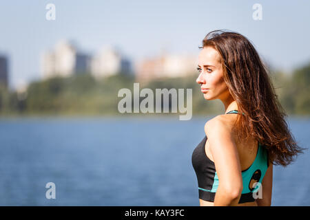 Portrait von jungen sportlichen Frau ausruhen nach dem Joggen im Park in der Nähe der See. Portrait von athletischen Mädchen in Schwarz top Nach dem Fitnesstraining. Gesunde lifestyl Stockfoto