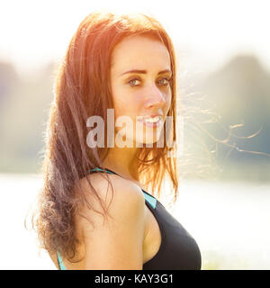 Portrait von jungen sportlichen Frau ausruhen nach dem Joggen im Park in der Nähe der See. Portrait von athletischen Mädchen in Schwarz top nach Fitness Workout Stockfoto