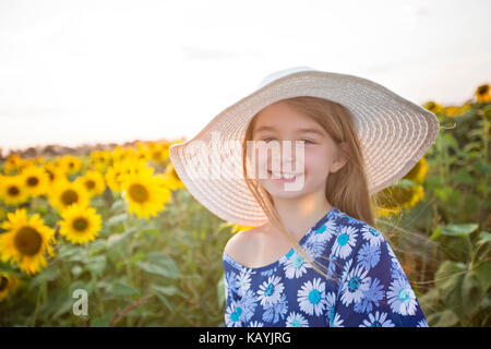 Glückliches Mädchen auf einem Feld mit Sonnenblumen im Sommer Sonnenuntergang Stockfoto