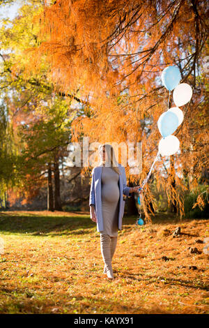 Hübsche junge schwangere Frau mit Ballons im Herbst Park Stockfoto