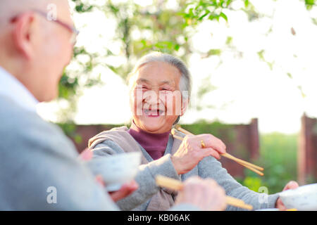 Glückliche und gesunde chinesische senior Paar zusammen essen im Garten Stockfoto