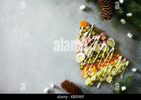 Weihnachtsbaum aus Salat Olivier auf grauem Schiefer, Stein oder Metall Hintergrund. Schöne Weihnachten und Neujahr Hintergrund für Lebensmittel, oben ein Stockfoto