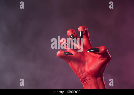 Red Devil hand mit schwarz glänzende Nägel, Halloween Theme Stockfoto