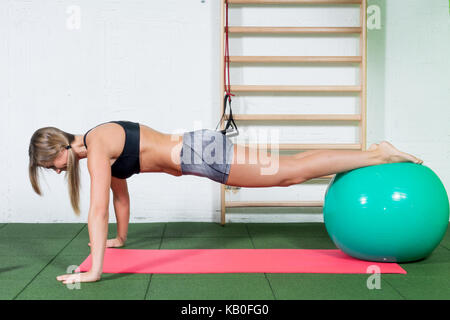 Schönen sport Mädchen tun stretching Fitness Übung auf Kugel bei Sport Fitnessraum, muskulös Mädchen tun Kreuz fit Workout im Fitnessraum. Stockfoto