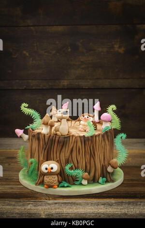 Verzauberten Wald Wald themed Fondant Kuchen mit einem Igel, Rehe, Owl, Baumstamm, Farne, Pilze und Blätter auf Holz- Hintergrund mit Copyspace Stockfoto