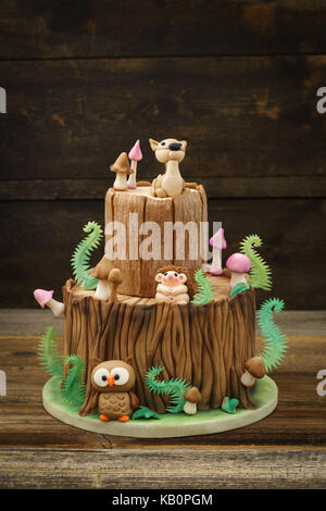 Verzauberten Wald Wald themed Fondant Kuchen mit einem Igel, Rehe, Owl, Baumstamm, Farne, Pilze und Blätter auf Holz- Hintergrund Stockfoto