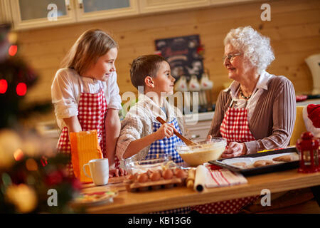 Lachenden Kindern und Großmutter Vorbereitung xmas Cookies - Familie Zeit Stockfoto