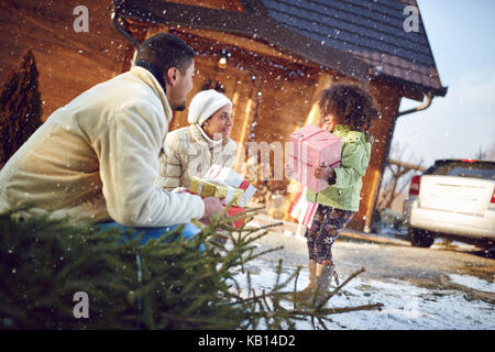 Afro-amerikanische kleine Mädchen hilft Eltern Kartons mit Geschenken im Mountain Haus zu bringen. Stockfoto