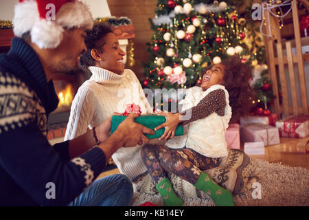 Glückliche Familie auf Weihnachten öffnen Geschenke auf dem Boden zu Hause sitzen Stockfoto