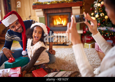 Glückliche kleine Mädchen mit Santa hat Ihre Mutter für Weihnachten Foto posiert Stockfoto