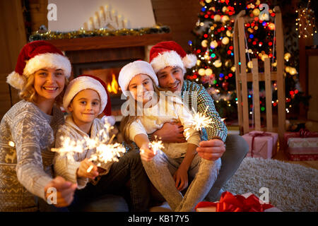 Familie, Weihnachten, Feiertage und Personen Konzept - glückliche Mutter, Vater und Kinder mit Wunderkerzen feiert Weihnachten Stockfoto