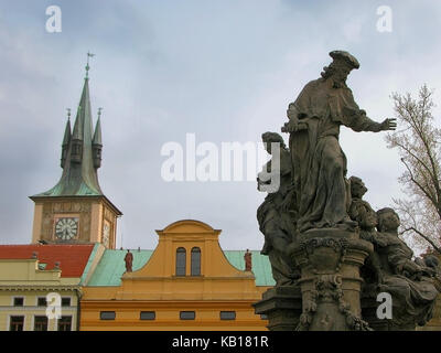 Statue auf der Karlsbrücke von St. Ivo, mit Häusern auf Novotného lávka und das alte Wasserwerk Clocktower jenseits, Staré Město, Prag, Tschechische Republik Stockfoto