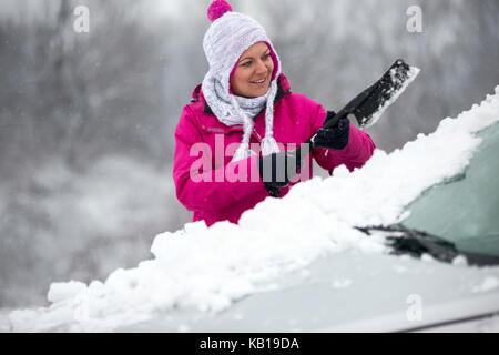 Frau Schneeräumung von Auto Windschutzscheibe Stockfoto