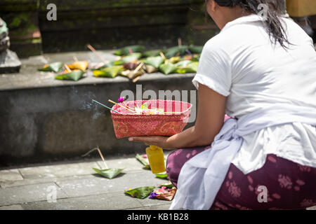 Die Frau, die mit den örtlichen Tempel auf Bali, Indonesien. mit Blumen und andere Geschenke ist sehr beliebte Tradition auf Bali. Stockfoto