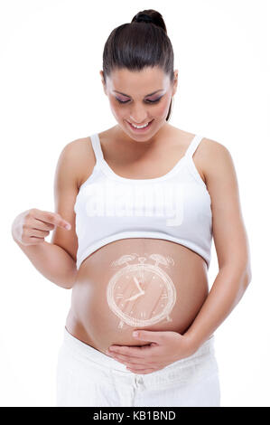 Schwangere Frau mit Uhr auf ihren Bauch, auf weißem Hintergrund Stockfoto