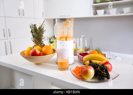 Gesunde smoothie Zutaten im Mixer mit frischem Obst am Küchentisch Stockfoto