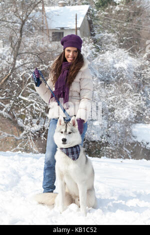 Junge Mädchen mit ihrem Husky im verschneiten Wald Stockfoto