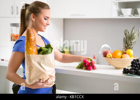 Die Frau in der Küche mit einer Einkaufstasche voller Frische Lebensmittel Stockfoto