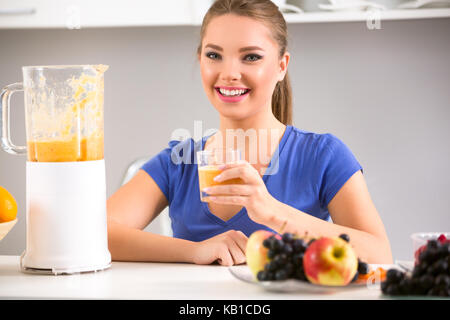 Schöne Frau mit einem Mixer mit Smoothie in der Küche. Stockfoto