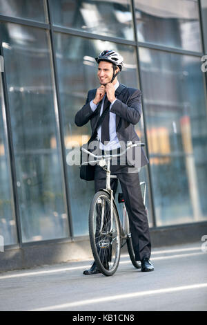 Geschäftsmann setzt das Fahrrad Helm auf dem Kopf Schutz auf dem Fahrrad Stockfoto