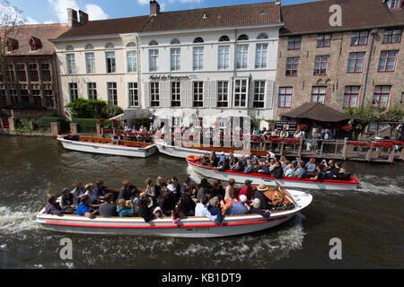 Stadt Brügge, Belgien. Malerische Ansicht von Touristen auf einem Kanal Boot Tour mit dem Hotel Orangerie im Hintergrund. Stockfoto