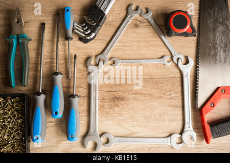 Haus der Schlüssel und unterschiedliche Tools auf hölzernen Hintergrund Stockfoto