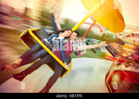 Junge glückliches Paar, das Spaß an Amusement Park, Reiten auf Karussell Stockfoto