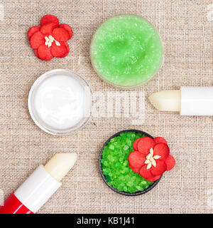Kosmetik für die Lippe Hautpflege: Meersalz, natürlicher Honig Peeling mit ätherischen Ölen, lip Cream und Balsame mit Blumen auf schäbigen Sack Serviette Stockfoto