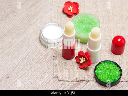Kosmetik für die Lippe Hautpflege: Meersalz, natürlicher Honig Peeling mit ätherischen Ölen, Lippenbalsame und Creme mit Blumen auf schäbige Holz- Oberfläche Stockfoto