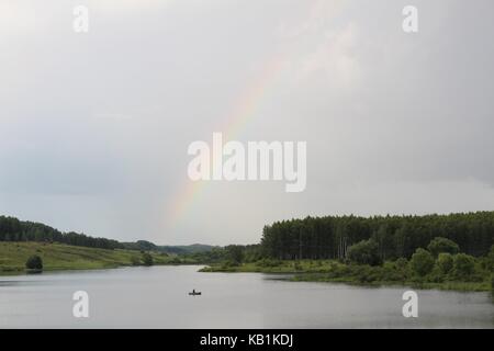 Ein schöner Regenbogen, der nach dem Regen über dem See erschien. Stockfoto