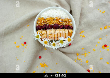 Ansicht von oben Müsli mit Nüssen, getrockneten Früchten und Gänseblümchen Stockfoto