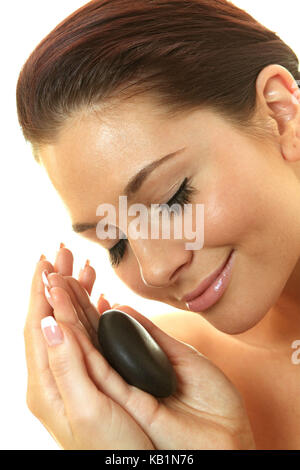 Junge hübsche Frau, die ihr Gesicht Massagen mit heißen Steinen, Stockfoto