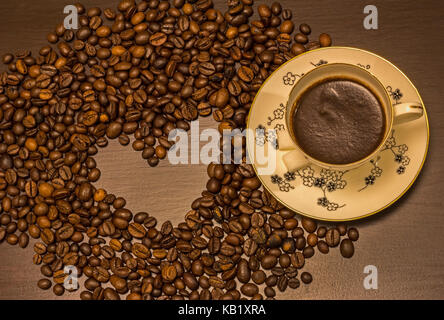 Herzform aus Kaffeebohnen hergestellt und eine Tasse Kaffee auf dem Tisch Stockfoto