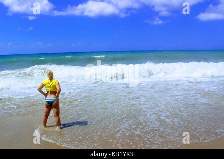 Juli, 2017 - eine Frau im gelben Trikot steht an der Küste in Cleopatra Beach (Alanya, Türkei). Stockfoto