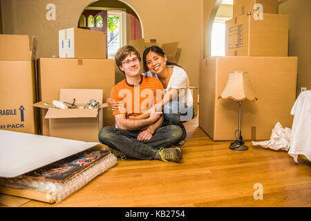 Portrait von ein glückliches junges Paar in ihrem neuen Zuhause von Ihren beweglichen Kästen umgeben. Stockfoto