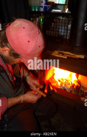 Ein angelführer Spalten von Holz und Gebäude ein Feuer an einem entfernten Fishing Camp in Alaska Stockfoto