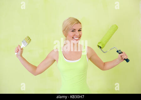 Glückliche Frau mit Paint roller über grüne Wand Stockfoto